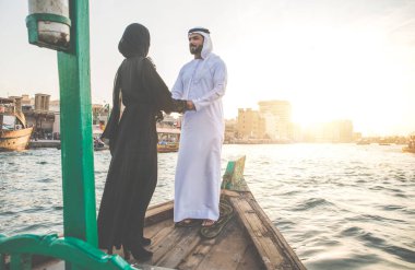 Mutlu çift Dubai'de zaman harcama. Nehrin üzerinde bir seyir alarak geleneksel kıyafetlerle kadın ve erkek