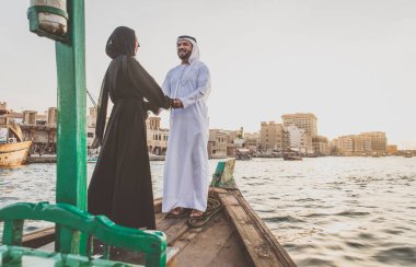 Mutlu çift Dubai'de zaman harcama. Nehrin üzerinde bir seyir alarak geleneksel kıyafetlerle kadın ve erkek