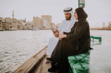 Mutlu çift Dubai'de zaman harcama. Nehrin üzerinde bir seyir alarak geleneksel kıyafetlerle kadın ve erkek