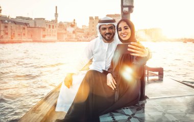 Mutlu çift Dubai'de zaman harcama. Nehrin üzerinde bir seyir alarak geleneksel kıyafetlerle kadın ve erkek