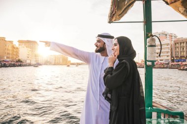 Mutlu çift Dubai'de zaman harcama. Nehrin üzerinde bir seyir alarak geleneksel kıyafetlerle kadın ve erkek