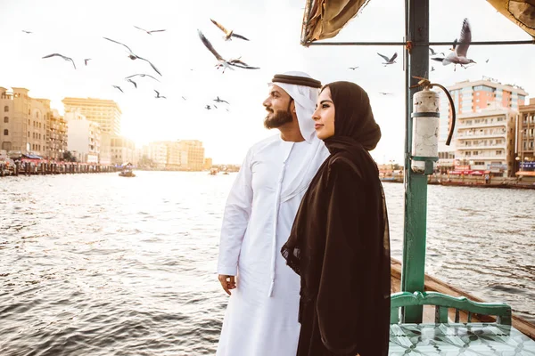 Mutlu çift Dubai'de zaman harcama. Nehrin üzerinde bir seyir alarak geleneksel kıyafetlerle kadın ve erkek