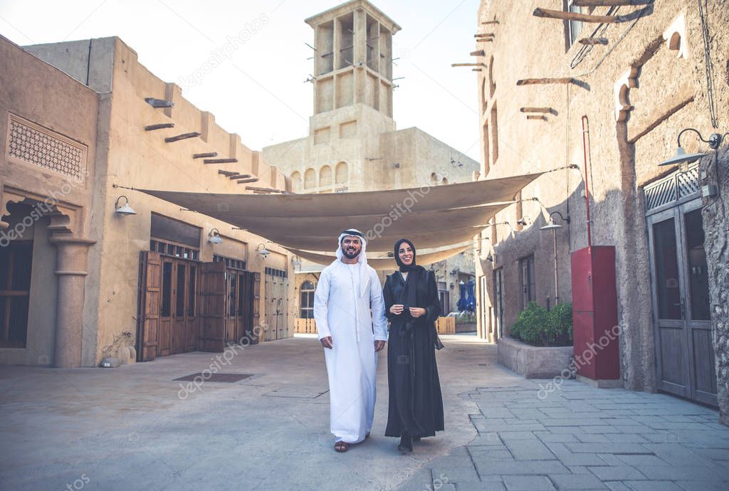 Happy couple spending time in Dubai. man and woman wearing traditional clothes making shopping in the old city