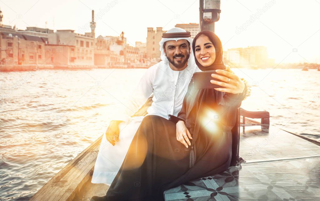 Happy couple spending time in Dubai. man and woman wearing traditional clothes taking a cruise on the river