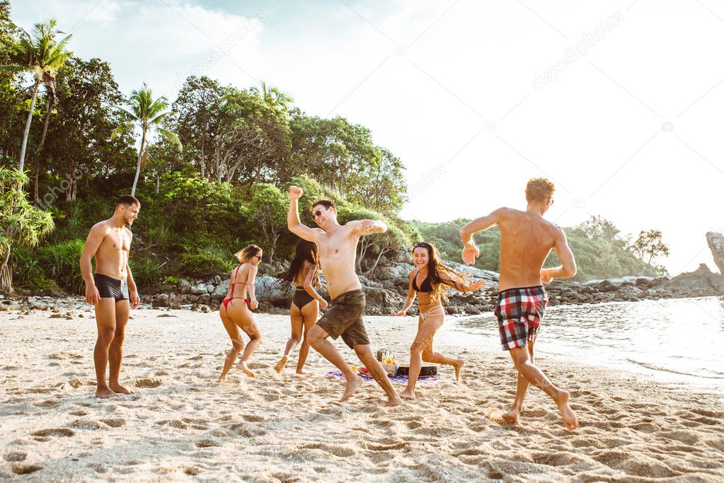 Group of friends having fun on the beach on a lonely island
