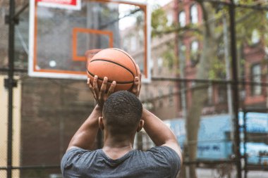 Afro-american basketball player training on a court in New York - Sportive man playing basket outdoors clipart