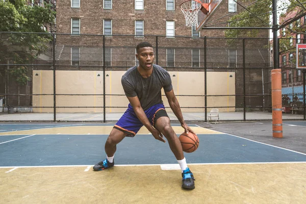 Afro-american basketball player training on a court in New York - Sportive man playing basket outdoors