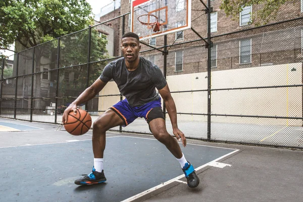 Afro-american basketball player training on a court in New York - Sportive man playing basket outdoors