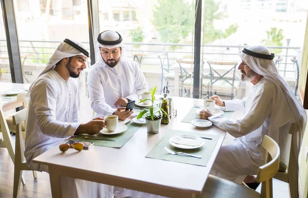 Group of middle eastern men wearing kandora bonding in a cafe\' restarant in Dubai