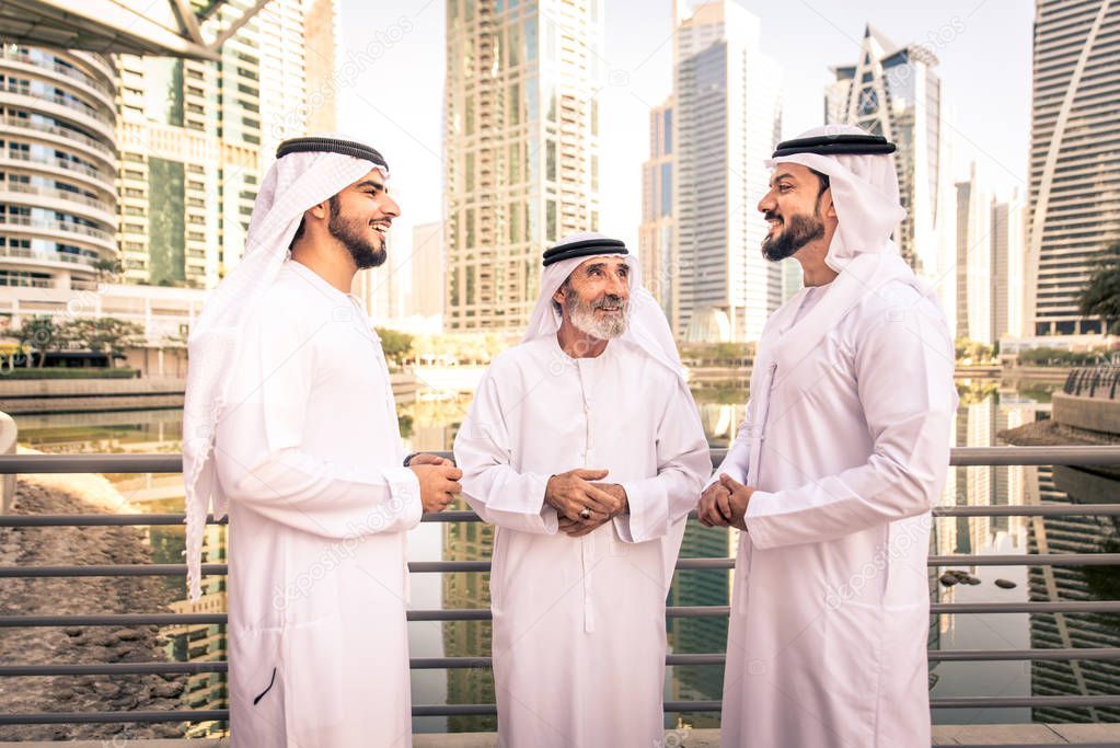 Group of arabian businessmen with kandura meeting outdoors in UAE - Middle-eastern men in Dubai