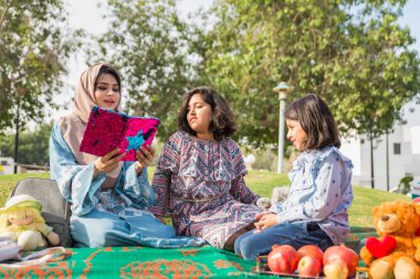 Dubai - anne kızları bir parkta birlikte eğleniyor mutlu Arap aile