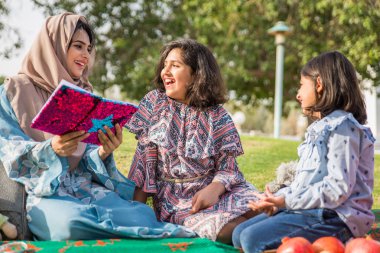 Dubai - anne kızları bir parkta birlikte eğleniyor mutlu Arap aile