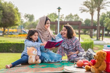 Dubai - anne kızları bir parkta birlikte eğleniyor mutlu Arap aile