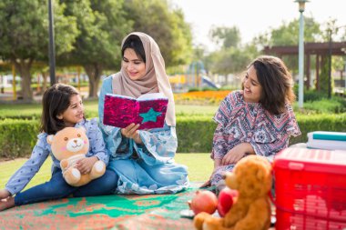 Dubai - anne kızları bir parkta birlikte eğleniyor mutlu Arap aile