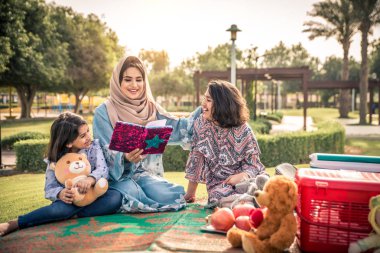 Dubai - anne kızları bir parkta birlikte eğleniyor mutlu Arap aile