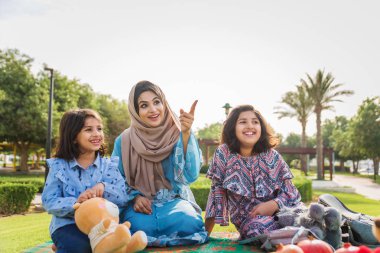 Dubai - anne kızları bir parkta birlikte eğleniyor mutlu Arap aile