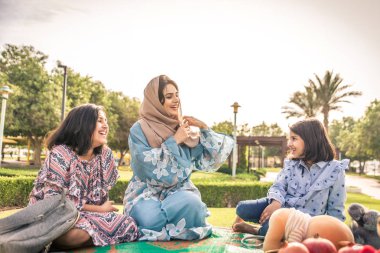 Dubai - anne kızları bir parkta birlikte eğleniyor mutlu Arap aile