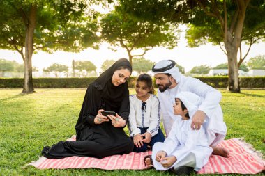 Dubai - ebeveynler ve çocuklar hafta sonu doğada kutluyor bir parkta eğleniyor mutlu bir Orta Doğulu aile