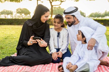 Dubai - ebeveynler ve çocuklar hafta sonu doğada kutluyor bir parkta eğleniyor mutlu bir Orta Doğulu aile