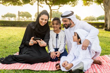 Dubai - ebeveynler ve çocuklar hafta sonu doğada kutluyor bir parkta eğleniyor mutlu bir Orta Doğulu aile