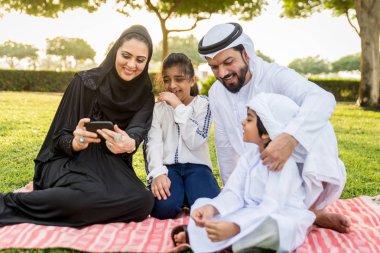 Dubai - ebeveynler ve çocuklar hafta sonu doğada kutluyor bir parkta eğleniyor mutlu bir Orta Doğulu aile