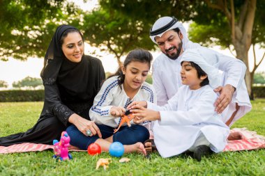 Dubai - ebeveynler ve çocuklar hafta sonu doğada kutluyor bir parkta eğleniyor mutlu bir Orta Doğulu aile
