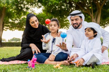 Dubai - ebeveynler ve çocuklar hafta sonu doğada kutluyor bir parkta eğleniyor mutlu bir Orta Doğulu aile