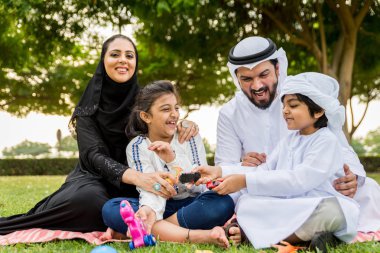 Dubai - ebeveynler ve çocuklar hafta sonu doğada kutluyor bir parkta eğleniyor mutlu bir Orta Doğulu aile
