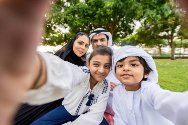 Dubai - ebeveynler ve çocuklar hafta sonu doğada kutluyor bir parkta eğleniyor mutlu bir Orta Doğulu aile