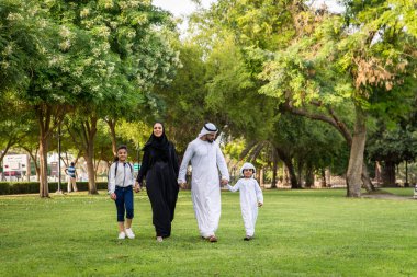 Dubai - ebeveynler ve çocuklar hafta sonu doğada kutluyor bir parkta eğleniyor mutlu bir Orta Doğulu aile