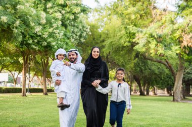 Dubai - ebeveynler ve çocuklar hafta sonu doğada kutluyor bir parkta eğleniyor mutlu bir Orta Doğulu aile