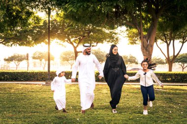 Dubai - ebeveynler ve çocuklar hafta sonu doğada kutluyor bir parkta eğleniyor mutlu bir Orta Doğulu aile