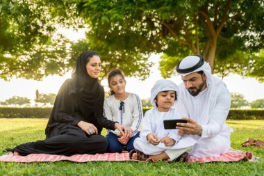 Dubai - ebeveynler ve çocuklar hafta sonu doğada kutluyor bir parkta eğleniyor mutlu bir Orta Doğulu aile