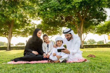 Dubai - ebeveynler ve çocuklar hafta sonu doğada kutluyor bir parkta eğleniyor mutlu bir Orta Doğulu aile