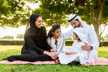 Dubai - ebeveynler ve çocuklar hafta sonu doğada kutluyor bir parkta eğleniyor mutlu bir Orta Doğulu aile