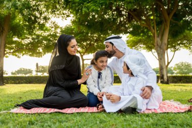 Dubai - ebeveynler ve çocuklar hafta sonu doğada kutluyor bir parkta eğleniyor mutlu bir Orta Doğulu aile