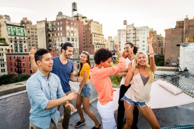 Mutlu gençler New York - parti ve eğlenerek arkadaş grubu bir çatıda bir barbekü akşam yemeği