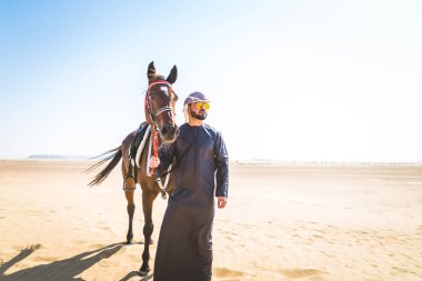 Yakışıklı adamla Orta Doğu: Dubai çölünde Arapça bir binicilik tipik Emirlikleri elbise