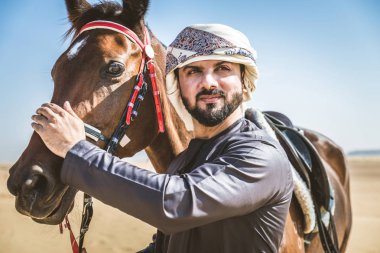 Yakışıklı adamla Orta Doğu: Dubai çölünde Arapça bir binicilik tipik Emirlikleri elbise