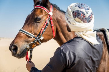 Yakışıklı adamla Orta Doğu: Dubai çölünde Arapça bir binicilik tipik Emirlikleri elbise