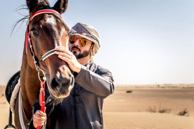 Yakışıklı adamla Orta Doğu: Dubai çölünde Arapça bir binicilik tipik Emirlikleri elbise