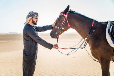 Yakışıklı adamla Orta Doğu: Dubai çölünde Arapça bir binicilik tipik Emirlikleri elbise
