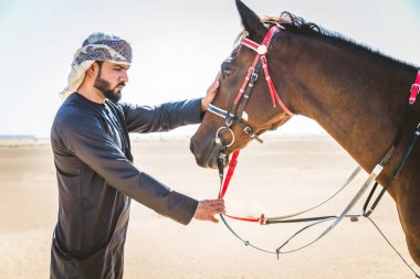 Yakışıklı adamla Orta Doğu: Dubai çölünde Arapça bir binicilik tipik Emirlikleri elbise