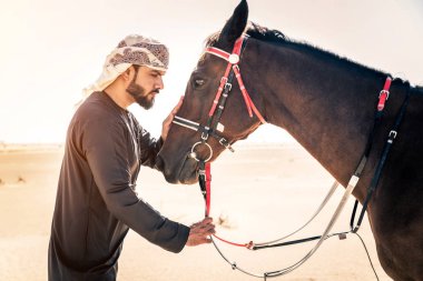 Yakışıklı adamla Orta Doğu: Dubai çölünde Arapça bir binicilik tipik Emirlikleri elbise
