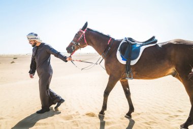 Yakışıklı adamla Orta Doğu: Dubai çölünde Arapça bir binicilik tipik Emirlikleri elbise