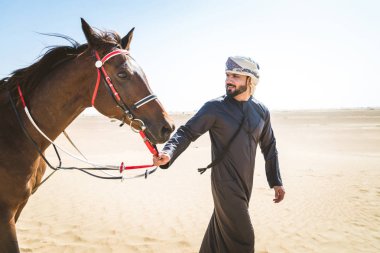 Yakışıklı adamla Orta Doğu: Dubai çölünde Arapça bir binicilik tipik Emirlikleri elbise