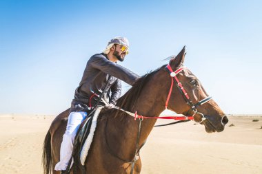 Yakışıklı adamla Orta Doğu: Dubai çölünde Arapça bir binicilik tipik Emirlikleri elbise