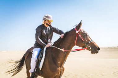 Yakışıklı adamla Orta Doğu: Dubai çölünde Arapça bir binicilik tipik Emirlikleri elbise