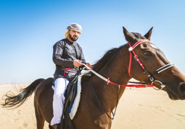 Yakışıklı adamla Orta Doğu: Dubai çölünde Arapça bir binicilik tipik Emirlikleri elbise