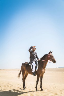 Yakışıklı adamla Orta Doğu: Dubai çölünde Arapça bir binicilik tipik Emirlikleri elbise
